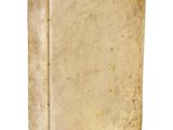 un vieux livre posé sur une table blanche à côté d'un mur blanc