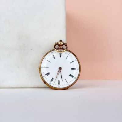 une montre de poche en or posée sur un bloc de marbre
