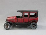 a red toy car that is sitting on a white surface