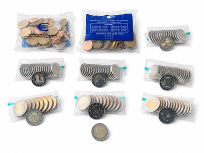 many different types of coins in bags on a white surface