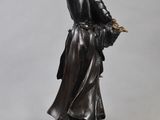 a bronze statue of a woman holding a bird on a pedestal