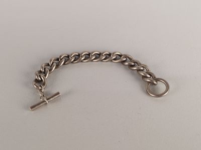 un gros plan d'un bracelet à maillons posé sur une surface blanche