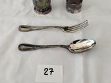 une tasse en argent et deux cuillères posées sur une table