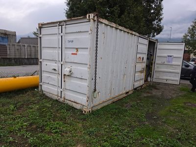 un récipient blanc posé dans l'herbe à côté d'un tuyau jaune