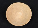 a wooden bowl on a black surface with a black background