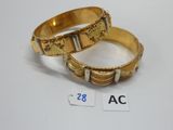 Deux bracelets en or sont présentés côte à côte sur une surface blanche