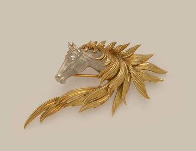 an image of a gold horse head broochle with leaves on it