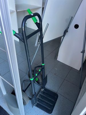 un diable noir avec une poignée verte dans une salle de bains