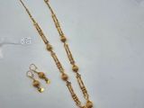 a gold necklace and earring set on a white surface