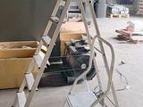 une échelle posée dans une pièce où se trouvent des cartons