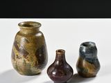 three vases sitting on a white table with a black background