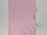 un t-shirt rose posé sur un fond blanc, avec une étiquette dessus
