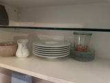 many plates and bowls on the shelves in the kitchen