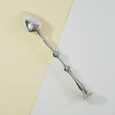 a silver spoon with a handle on a yellow and white surface