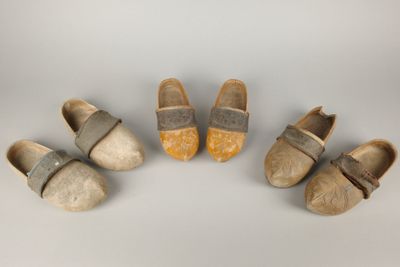quatre paires de sabots sont alignées sur une surface blanche