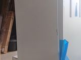 an image of a white refrigerator in a room that is under construction