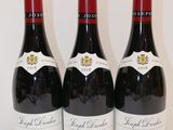 trois bouteilles de vin rouge sont alignées sur une table
