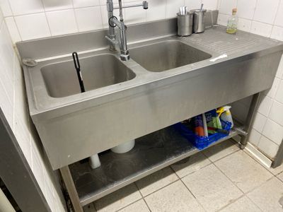 two sinks in the kitchen with a metal shelf
