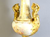 a gold vase with a statue on it on a stand
