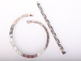 deux bijoux en argent posés sur une surface blanche, à côté d'une paire de ciseaux