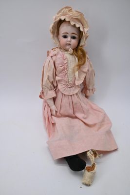 doll sitting on the floor wearing a pink dress and hat
