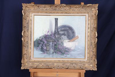 une photo d'un tableau posé sur un chevalet, avec une bouteille de vin