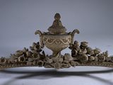 a large ornate vase on a stand on a white table