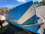 a blue boat that is sitting on the side of the road