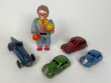 cinq petites voitures et une figurine de clown posées sur une surface blanche