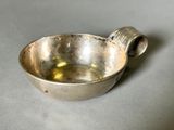 un petit bol en argent avec une anse sur une table