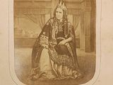 an old photograph of a woman in a regal dress sitting on a chair