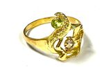 bague plaquée or ornée de pierres vertes et blanches sur un fond blanc