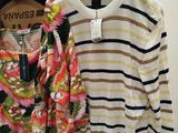 two sweaters hanging on a rack in a store