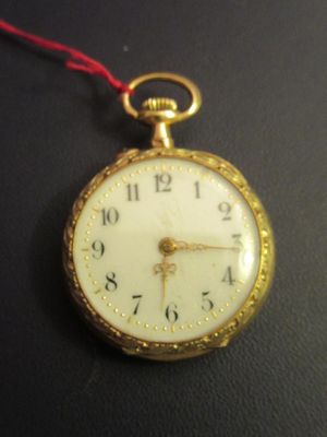 a close up of a gold pocket watch on a black surface