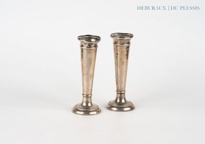 une paire de bougeoirs en argent posés sur une surface blanche, sur fond blanc