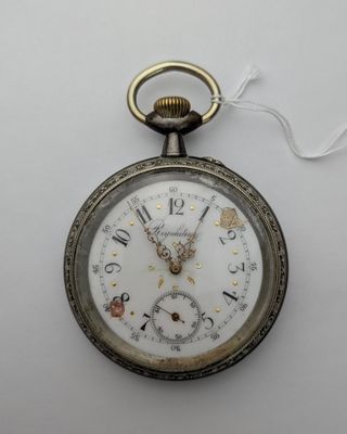 une vieille montre de poche à laquelle est accrochée une chaîne sur le côté