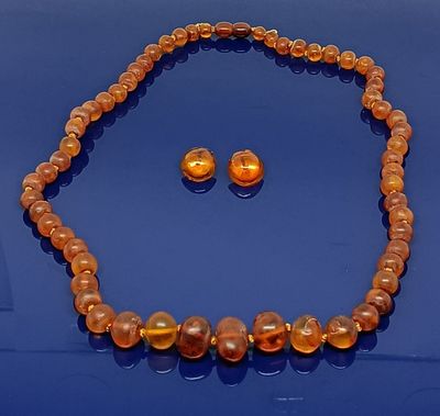 une photo d'un ensemble composé d'un collier et de boucles d'oreilles, posée sur un fond bleu