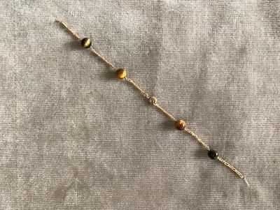 un gros plan d'un bracelet orné de perles, posé sur un tissu