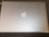 un ordinateur portable Apple posé sur une table, à côté d'un chargeur