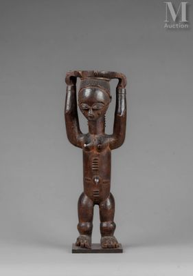 a wooden statue of a man holding a basket on his head