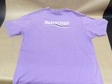 purple t - shirt with white logo on it sitting on a chair