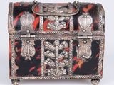 a silver and tortoise shell box sitting on a white surface