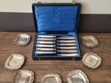 a set of six silver plated knives in a case on a table