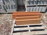 several pieces of wood are stacked on a pallet in front of a pile of concrete blocks