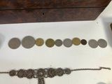 a lot of coins and a bracelet on a table