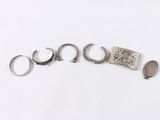 three silver rings and a silver coin on a white surface