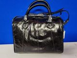 un sac à main en cuir noir posé sur une table blanche