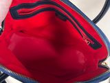 a person holding a red purse with a black handle