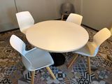 une table blanche entourée de quatre chaises dans une pièce