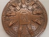 une médaille de bronze sur laquelle sont représentées des mains, posée sur un fond blanc